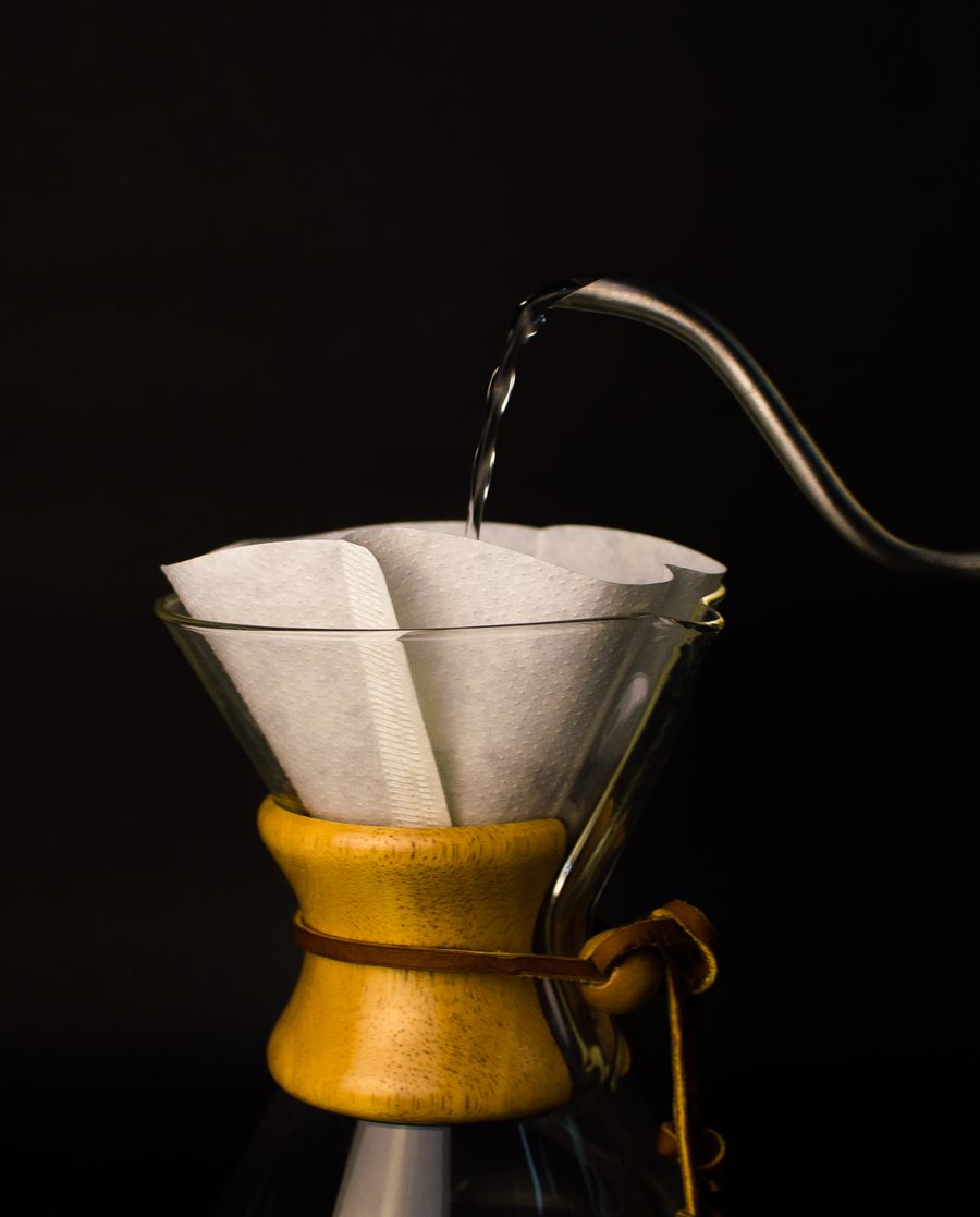 Cafea filtru turnată manual peste un filtru de hârtie, cu fum ridicându-se din lichid